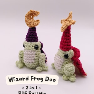 Może przedstawiać: Dwie szydełkowe figurki żab, jedna z fioletowym kapeluszem i półksiężycem, druga z czerwonym kapeluszem i gwiazdą. Żaby są jasnozielone i białe, z czarnymi oczami. Widoczny jest tekst "Wizard Frog Duo" i "2-in-1 PDF Pattern".