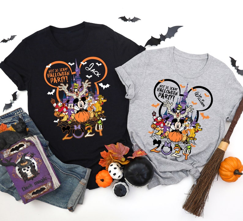 May include: Two t-shirts with a Halloween design. One is black, the other gray. Both feature a graphic of Disney characters, a pumpkin, and the text "NOT SO SCARY HALLOWEEN PARTY!" and "2024". The black shirt has the name "Jack", and the gray shirt has the name "William".