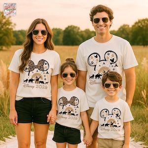 May include: Four people wearing matching off-white t-shirts with a Disney-themed design. The shirts feature a Mickey Mouse head silhouette with animal silhouettes, a tree, and the text "Disney 2026". The women's shirt has a leopard print bow.
