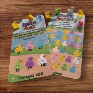 May include: A colourful game card with a yellow rubber duck on the front. The card says "Hook a duck" and has a chart with different coloured ducks and their corresponding values in pounds. The card also says "Total saved £120".