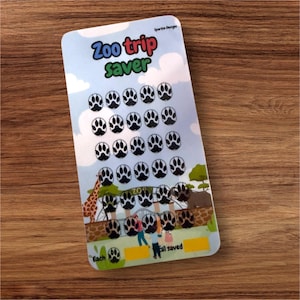 May include: A blue and white card with the text "Zoo Trip Saver" and a grid of paw print stickers. The card has a picture of a zoo entrance with a giraffe, elephant, and people.
