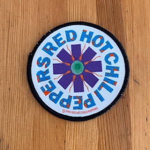 May include: A circular patch with the text "RED HOT CHILI PEPPERS" in blue and orange lettering. The patch features a purple asterisk design with a green center. The text "© 1993 RED HOT CHILI PEPPERS" is at the bottom.