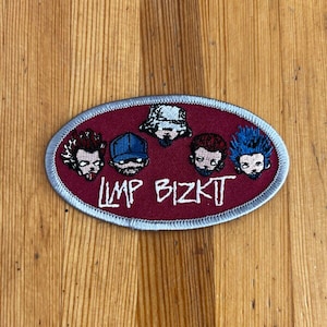 Könnte beinhalten: Ein ovaler gestickter Aufnäher mit rotem Hintergrund und silbernem Rand. Der Aufnäher zeigt fünf Comic-Gesichter von Bandmitgliedern und den Text "Limp Bizkit" in Weiß.