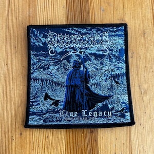 May include: A square, blue patch with black trim featuring the band name "Dissection" in white gothic lettering. The image depicts a robed figure with a scythe, the text "Live Legacy" and "Nuclear Blast 2003".