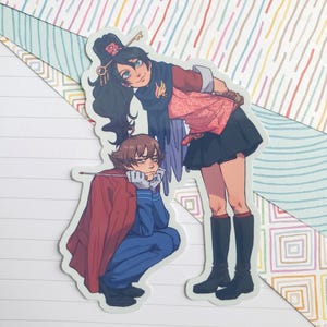 以下が含まれることがあります： 2人のアニメ風キャラクターのステッカー。一人は赤いコートを着た青い衣装でひざまずき、もう一人は黒いスカートとブーツを履いた赤とピンクの衣装で立っています。背景はカラフルな模様です。