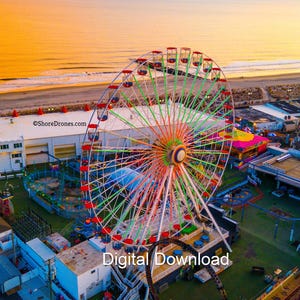 May include: An aerial view of a brightly coloured Ferris wheel at a seaside amusement park at sunset. The wheel has red, green, and orange accents. The text "Digital Download" is at the bottom of the image.