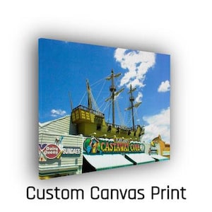May include: A canvas print featuring a pirate ship facade with the text "Castaway Cove" and "Dairy Queen Sundaes" under a bright blue sky with clouds. The words "Custom Canvas Print" are at the bottom.