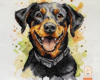 May include: A cross-stitch pattern featuring a black and tan dog with a wide, happy grin and an open mouth. The dog wears a dark collar and is set against a watercolor-style background of yellow and green splashes on white fabric. Includes PDF icon.