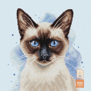 May include: A cross-stitch pattern featuring a Siamese cat with dark brown ears and face, bright blue eyes, and a cream-colored body. The cat is set against a light blue background with scattered blue pixelated squares and a PDF icon in the corner.
