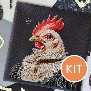 Può includere: Kit per punto croce con un ritratto di gallo. Il gallo ha cresta e bargigli rossi e indossa un colletto decorativo. Il kit è su sfondo grigio scuro, con la scritta "KIT" in un cerchio arancione.