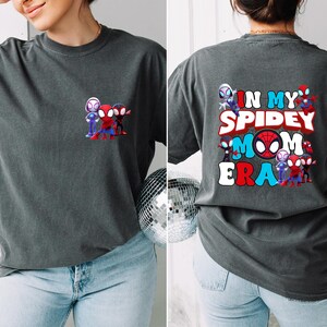 Puede incluir: Una camiseta gris oscuro con un gr&aacute;fico de personajes de Spider-Man de dibujos animados y el texto "In My Spidey Mom Era".