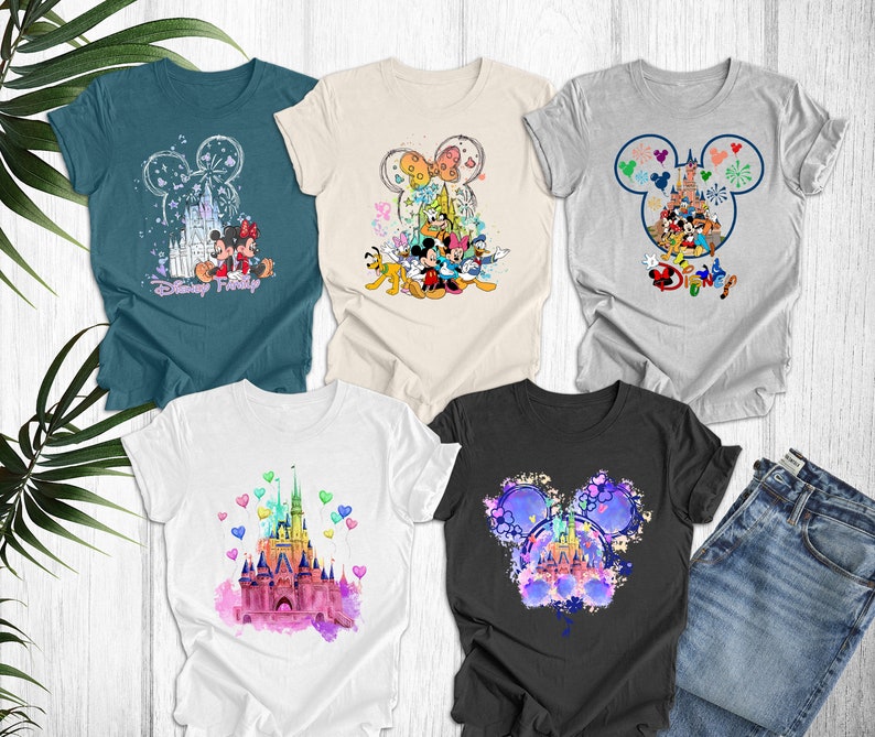 May include: Five different t-shirts featuring various Disney characters and designs. The shirts are all white, grey, black, and teal. The designs include Mickey Mouse, Minnie Mouse, Donald Duck, Goofy, Pluto, and Cinderella's castle. The shirts are all printed with the word "Disney" on them.