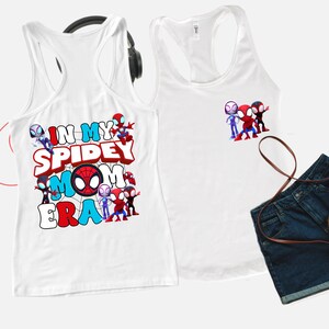 Puede incluir: Dos camisetas sin mangas blancas. Una camiseta sin mangas tiene un gr&aacute;fico de personajes de Spider-Man y el texto "In My Spidey Mom Era". La otra camiseta sin mangas tiene un gr&aacute;fico de personajes de Spider-Man.