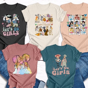 May include: Five different t-shirts featuring various Disney characters. The shirts are in a variety of colours and all have the text "Let's Go Girls" printed on them.