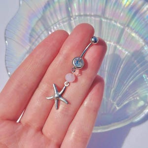 May include: Silver belly button ring with a clear crystal, a pink bead, and a silver starfish charm.
