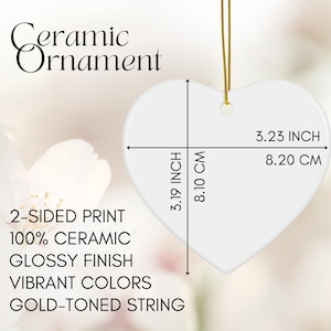 May include: A white heart-shaped ceramic ornament with a glossy finish, 3.19 inches wide and 3.23 inches tall. It has a gold-toned string for hanging. The text on the ornament says "Ceramic Ornament", "2-SIDED PRINT", "100% CERAMIC", "GLOSSY FINISH", "VIBRANT COLORS", and "GOLD-TONED STRING".