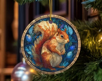 May include: Round Christmas ornament featuring a detailed illustration of a squirrel. The squirrel has reddish-brown fur and is set against a blue and white floral background. The ornament is trimmed with a gold border and a gold hanging string.
