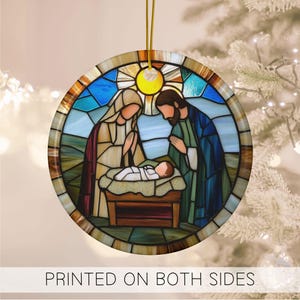 May include: A stained glass style Christmas ornament featuring the Holy Family. Mary, Joseph, and baby Jesus are depicted in a colorful, circular design. The ornament is printed on both sides.