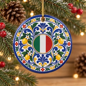 Op de afbeelding: Een rond keramisch ornament met een centrale cirkel in de kleuren van de Italiaanse vlag groen, wit en rood. Het ontwerp is omringd door blauwe, gele en groene florale krulpatronen en gele citroenillustraties met witte bloesems.