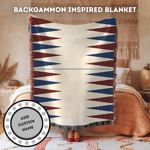 Könnte beinhalten: Eine weiße gewebte Decke mit einem Backgammon-Brett-Design. Die Decke hat ein rotes und blaues geometrisches Muster. Die Decke ist über ein Bett mit einem braunen und weißen Kissen gelegt. Der Text "ADD CUSTOM NAME" befindet sich auf einem weißen Kreis mit einem grauen Rand.