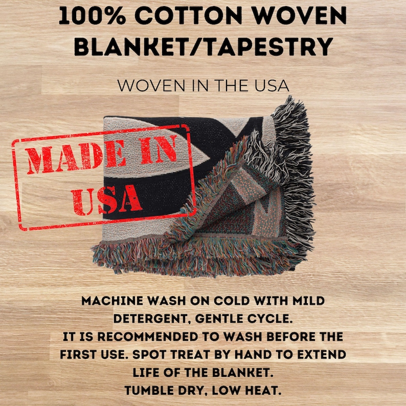 May include: A folded black and beige woven blanket/tapestry with fringe. The blanket has a geometric design and the text "MADE IN USA" is stamped on it. The blanket is made of 100% cotton and is machine washable.