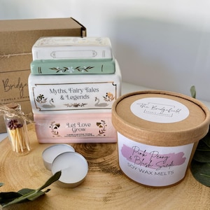 May include: A collection of decorative book-shaped boxes with floral and swan designs, and the text "Myths, Fairy Tales & Legends" and "Let Love Grow". A container of soy wax melts, tea lights, and a small glass bottle of matches.
