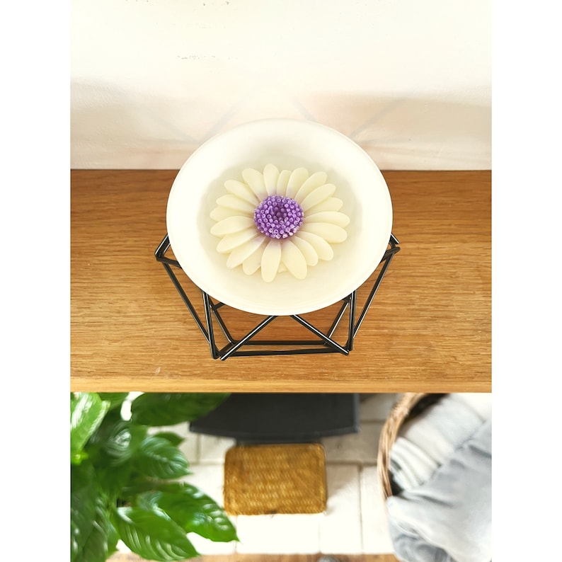 May include: White ceramic wax melt warmer with a purple and white flower design. The warmer is on a black geometric stand.