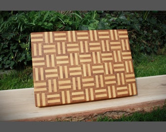 May include: A wooden cutting board with a woven pattern in shades of brown and yellow.