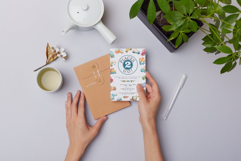 May include: A white envelope with a brown paper envelope inside. The brown envelope has a string tied around it with two brass grommets. The white envelope has a colorful invitation with the text "Places 2 Go!" and a design of toy vehicles.