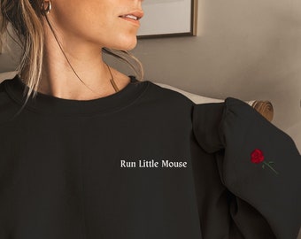 May include: Black sweatshirt with the text "Run Little Mouse" in white. A small embroidered red rose is on the left sleeve. The sweatshirt is a casual, comfortable style.