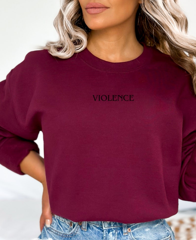 Może przedstawiać: Bordowa bluza z haftem z napisem "VIOLENCE" z przodu.