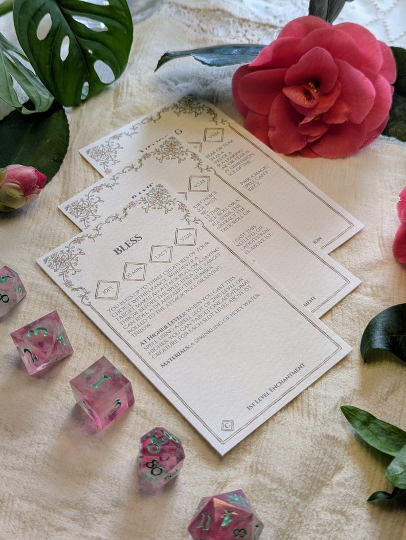May include: A white card with the words "Bless" and "30ft" printed on it. The card is decorated with a floral design and has a light pink background. The card is part of a set of cards that are used for a role-playing game.