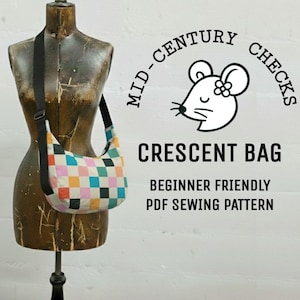 Op de afbeelding: Een halvemaanvormige tas met een kleurrijk ruitpatroon en een zwarte band wordt getoond op een vintage paspop. De tas heeft vierkanten in verschillende kleuren. De afbeelding bevat tekst die luidt "Mid-Century Checks" en "Crescent Bag, Beginner Friendly PDF Sewing Pattern."