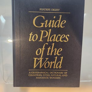 May include: A navy blue hardcover book titled "Guide to Places of the World" by Reader's Digest. The title and author's name are in gold lettering. The book is a geographical dictionary of countries, cities, natural and man-made wonders.