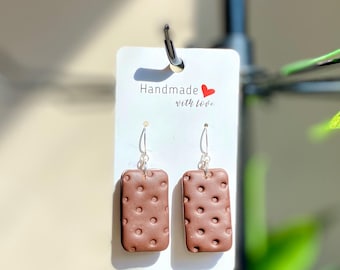 May include: Brown rectangular earrings with a dotted pattern, hanging from silver hooks. The earrings are displayed on a white card with the text "Handmade with love" and a red heart.
