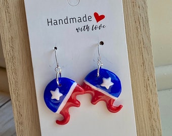 May include: Handmade earrings with a patriotic theme. The earrings feature a blue and red design with a white star. The text "Handmade with love" is printed on the white card.