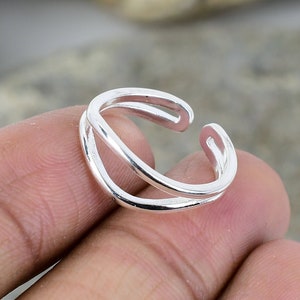May include: A silver adjustable ring with a double band design.