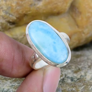 May include: A silver ring featuring a light blue oval-shaped gemstone. The gemstone has a marbled pattern.