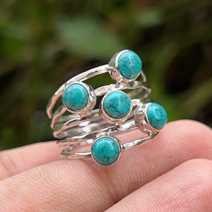 Peut inclure: Une bague en argent avec cinq pierres turquoise serties dans un design de bande empilée.
