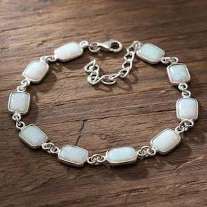 May include: A silver bracelet with rectangular opal stones. The opals are set in silver bezels and linked together. The bracelet has a lobster clasp. The opals are milky white with flashes of iridescent colour. A beautiful piece of jewellery.