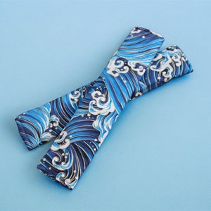 May include: A pair of blue and white fabric wrist cuffs with a wave pattern. The cuffs are made of a soft, comfortable material and are perfect for adding a touch of style to any outfit.