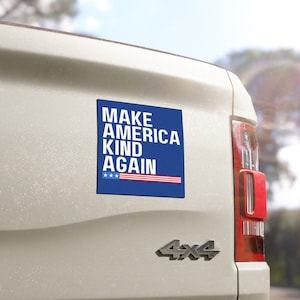 May include: A blue and white car magnet with the text "MAKE AMERICA KIND AGAIN" and a small American flag.