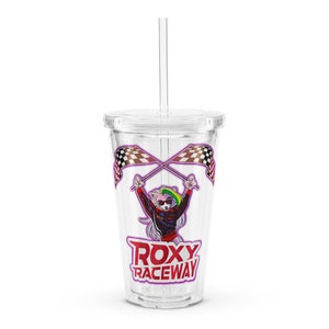 Puede incluir: Un vaso transparente de plástico con tapa y pajita. El vaso tiene un gráfico colorido de un personaje de dibujos animados sosteniendo banderas a cuadros con el texto "ROXY RACEWAY" impreso debajo.