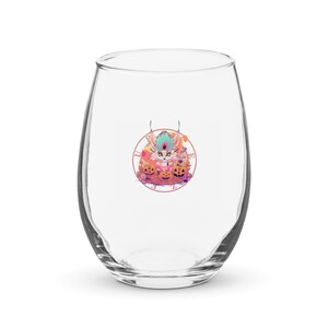 May include: A clear stemless wine glass with a Halloween-themed design. The design features a cartoon character with pumpkins and the text "PURPLE". The glass is empty and sits on a white surface.