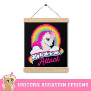 Puede incluir: Una impresión en lienzo negro con un unicornio blanco con una crin y cola rosadas. El unicornio está rodeado de un arcoíris y nubes. El texto "My Little Panic Attack" está escrito en letras rosas y blancas.