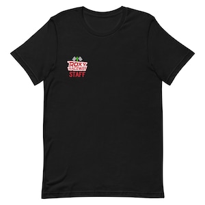 Puede incluir: Camiseta negra con un logotipo rojo y blanco que dice "ROXY RACEWAY STAFF" con una bandera verde y una bandera a cuadros.
