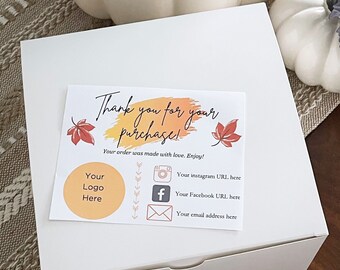 May include: A white square box with a thank you card on top. The card has text that says "Thank you for your purchase!" with fall leaf illustrations and social media icons. A logo circle is also present.