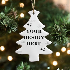 May include: White ceramic Christmas tree ornament with a string hanging from the top. The ornament has a design of stars and the text "YOUR DESIGN HERE".