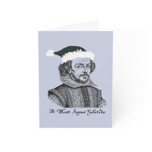 Puede incluir: Tarjeta de felicitación con una ilustración en blanco y negro de William Shakespeare con un gorro de Papá Noel verde y blanco. El texto "A Most Joyous Yuletide" está impreso en la parte inferior.