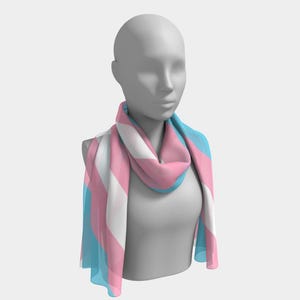 May include: A scarf draped on a mannequin, featuring a design with vertical stripes in light blue, pink, and white. The scarf is made of a lightweight material, with the colors representing the transgender pride flag.